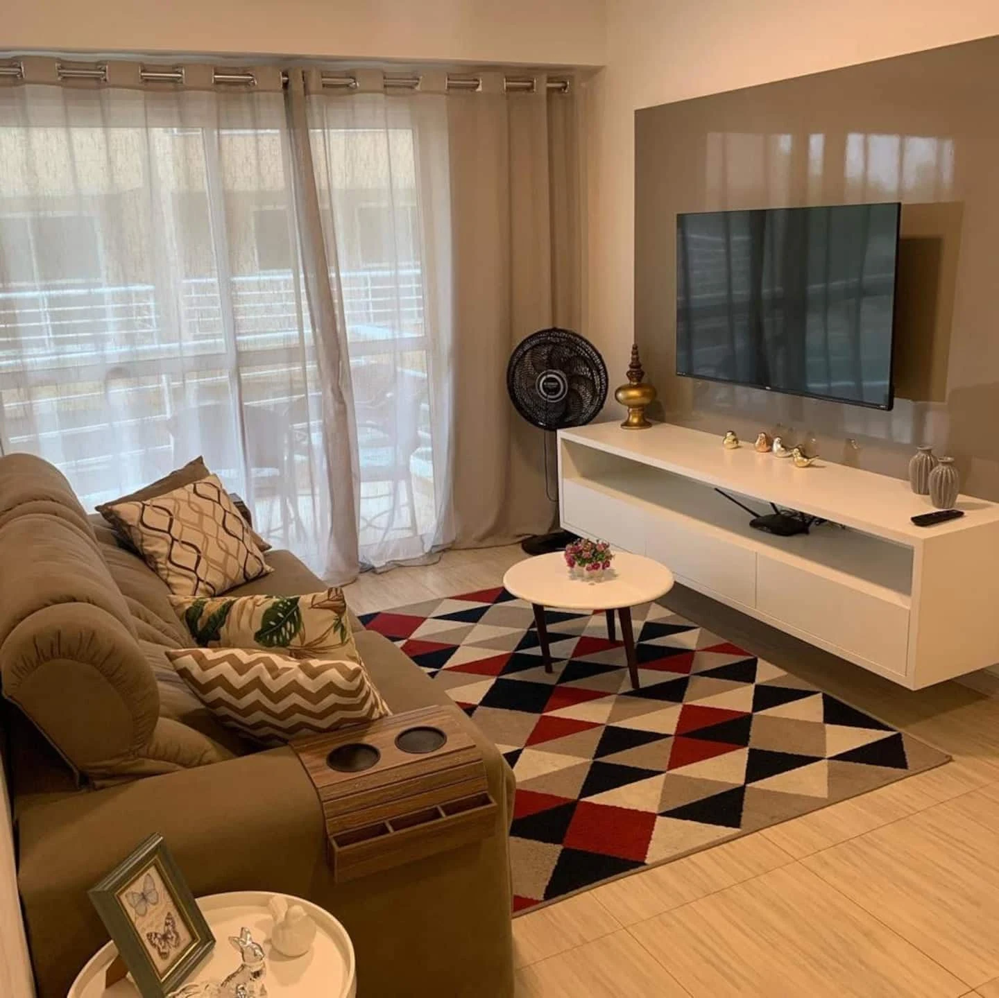 Sala real do apartamento à venda, com sofá, tapete geométrico e acesso à varanda