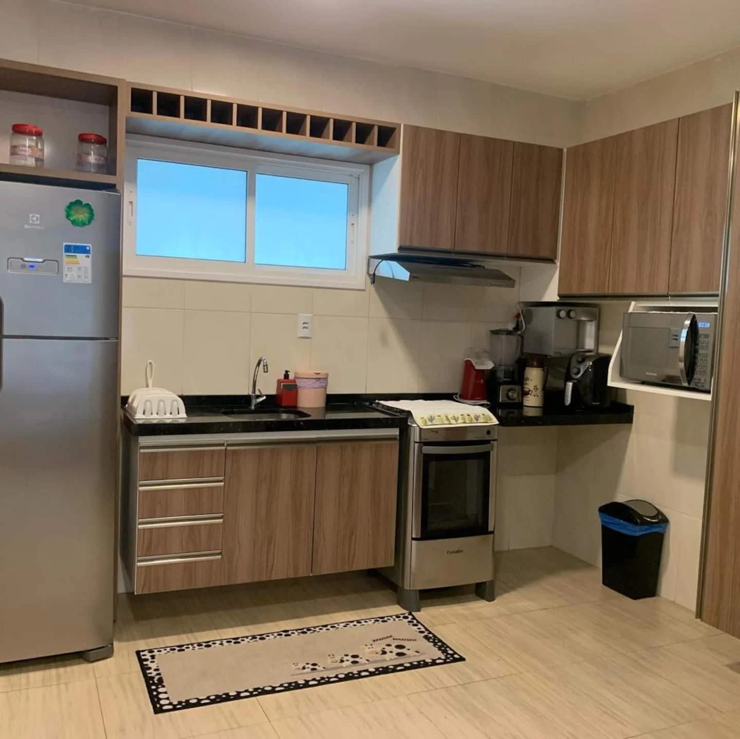 Cozinha real com bancada, armários de madeira, geladeira, fogão e micro-ondas